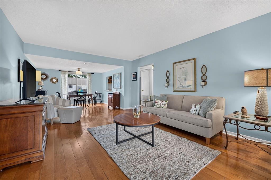 A living room with light blue walls, hardwood floors, a gray area rug, and furniture — 2490 HERON TERRACE UNIT #F203, CLEARWATER, FL