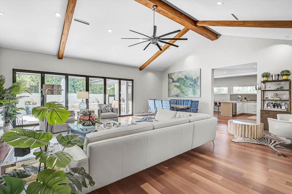 A spacious living room features vaulted ceilings with exposed wooden beams and hardwood flooring — 627 OWL WAY, SARASOTA, FL