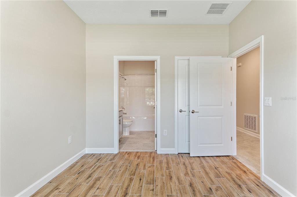 A room with wood-look tile flooring, a bathroom doorway, a closet door, and an entryway — 1064 BLACKWOLF RUN ROAD, DAVENPORT, FL