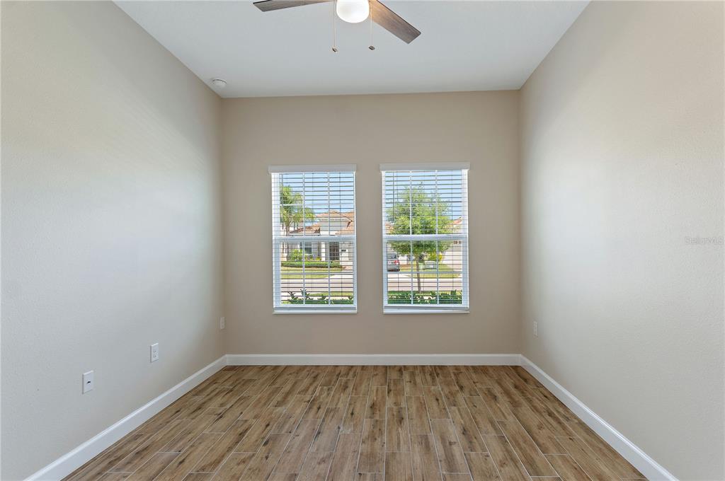 An empty room features light-colored walls, wood-look tile flooring, two windows, and a ceiling fan — 1064 BLACKWOLF RUN ROAD, DAVENPORT, FL