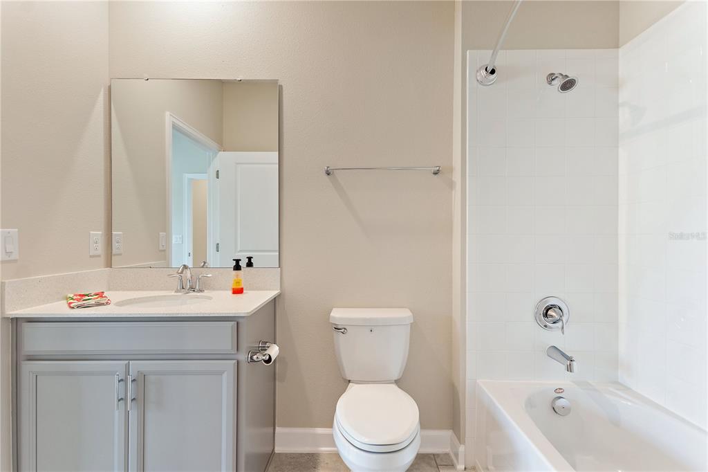 A bathroom features a gray vanity, a toilet, and a white tiled shower-tub combination — 1064 BLACKWOLF RUN ROAD, DAVENPORT, FL