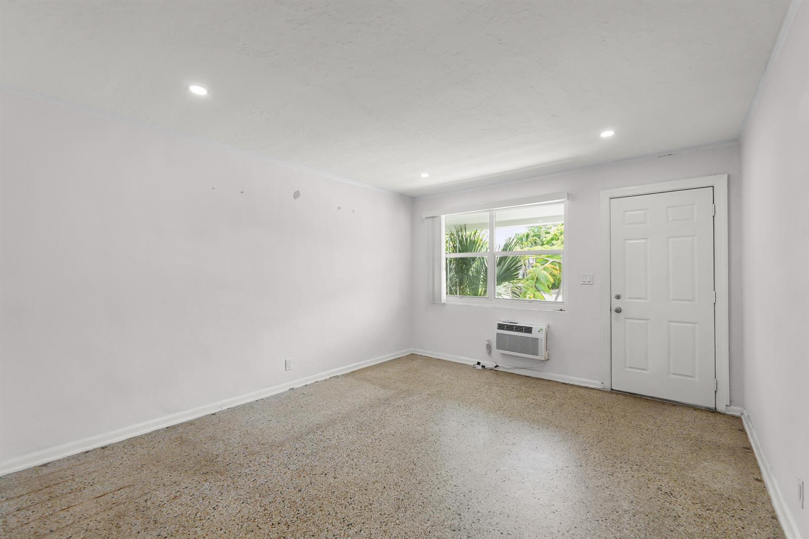 A sparsely furnished room with white walls, a speckled floor, a window, and a door — 429 Lytle Street, West Palm Beach FL 33405, WEST PALM BEACH, FL