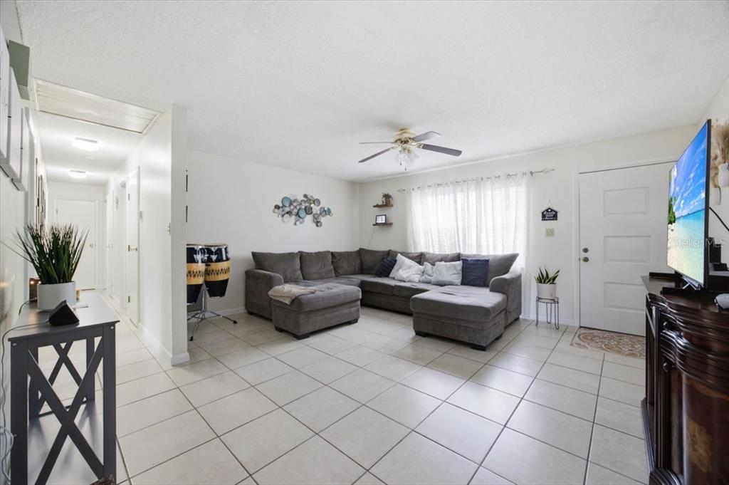 A living room features a gray sectional sofa, tile flooring, and a ceiling fan — 2266 LAKE LIZZIE COURT, ST CLOUD, FL