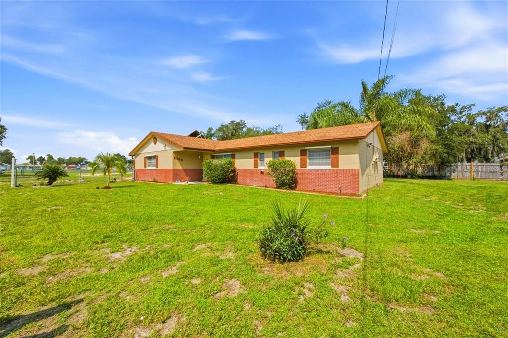 A single-story house with a brick and tan exterior sits on a large grassy lot — 2266 LAKE LIZZIE COURT, ST CLOUD, FL