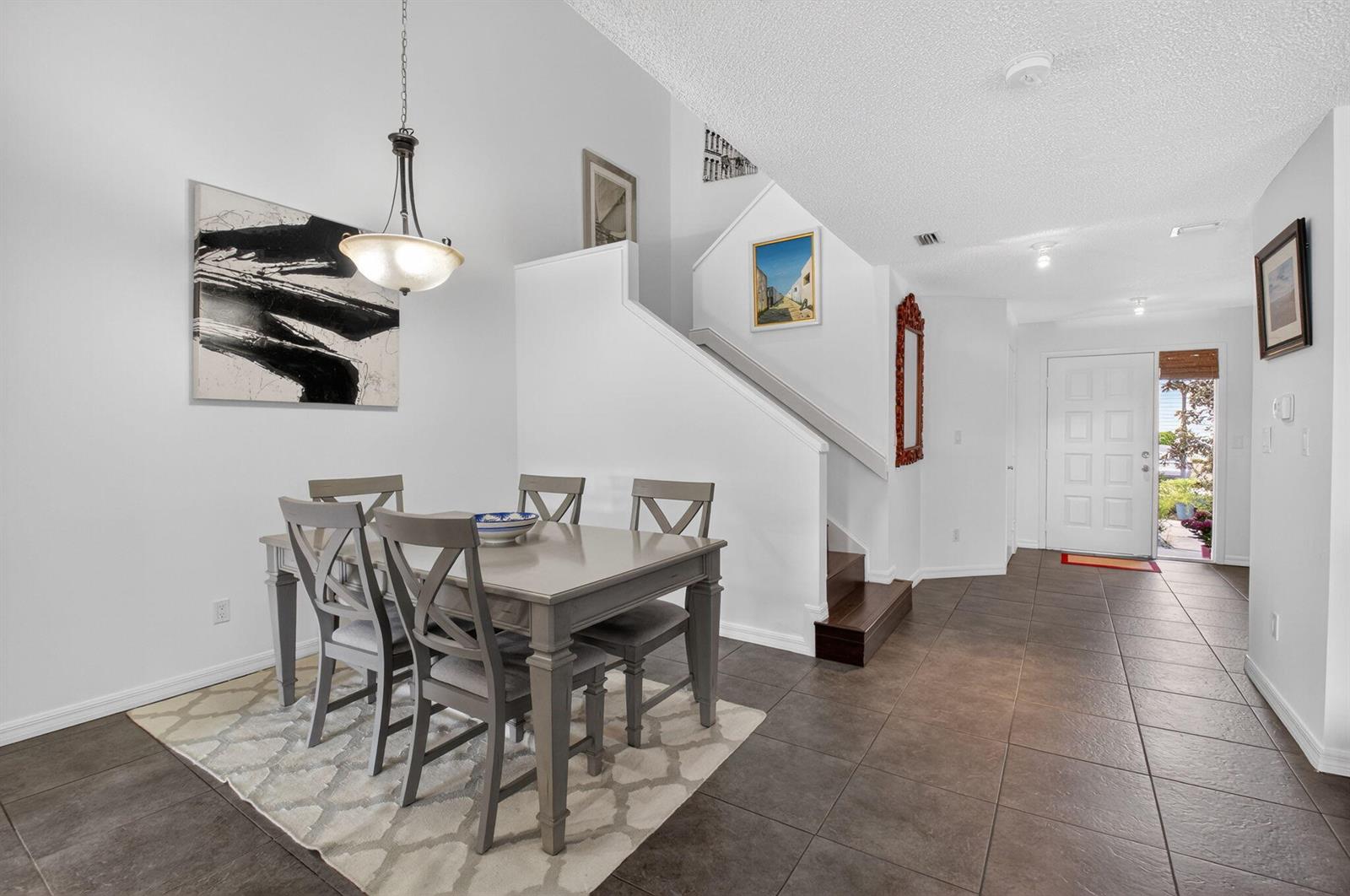 A dining area with a gray table and chairs sits on a rug near stairs — 5282 Sapphire Valley, Boca Raton FL 33486, BOCA RATON, FL
