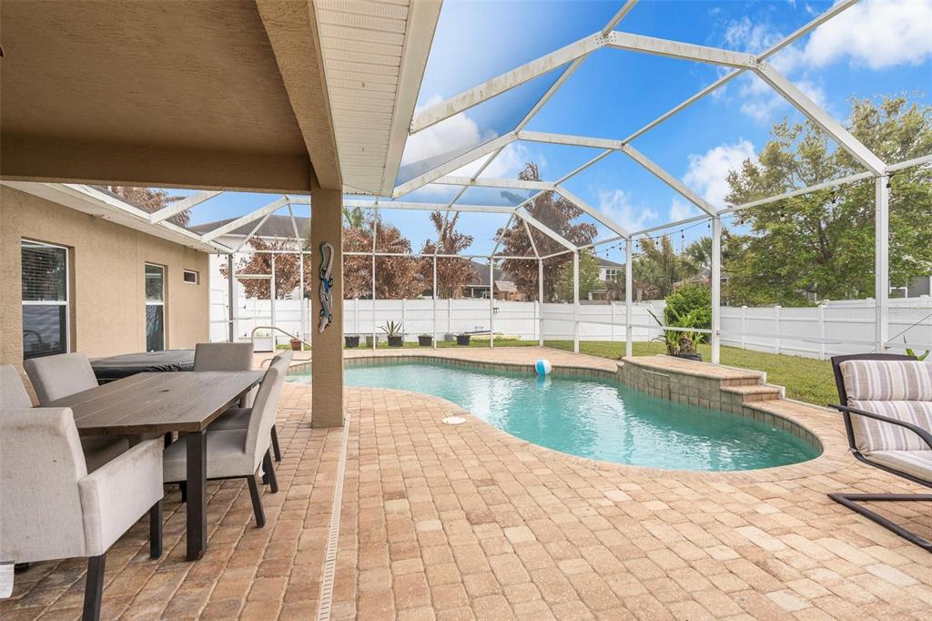 A covered patio with a dining set overlooks a swimming pool inside a screened enclosure — 6970 VINTAGE LANE, PORT ORANGE, FL