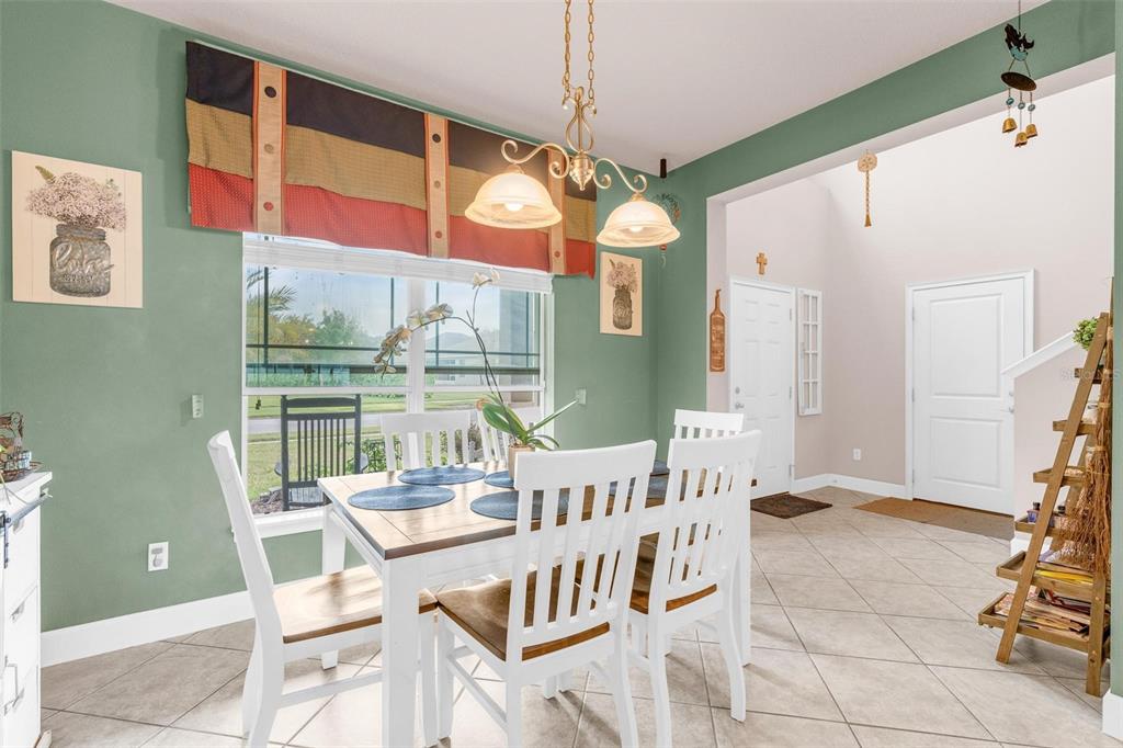 A dining area with a white table, chairs, green walls, and a window with valance — 6970 VINTAGE LANE, PORT ORANGE, FL