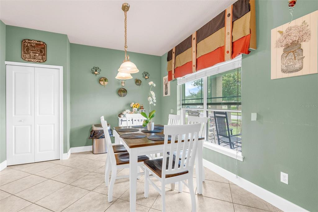 A dining room features a wooden table, white chairs, green walls, and a large window — 6970 VINTAGE LANE, PORT ORANGE, FL