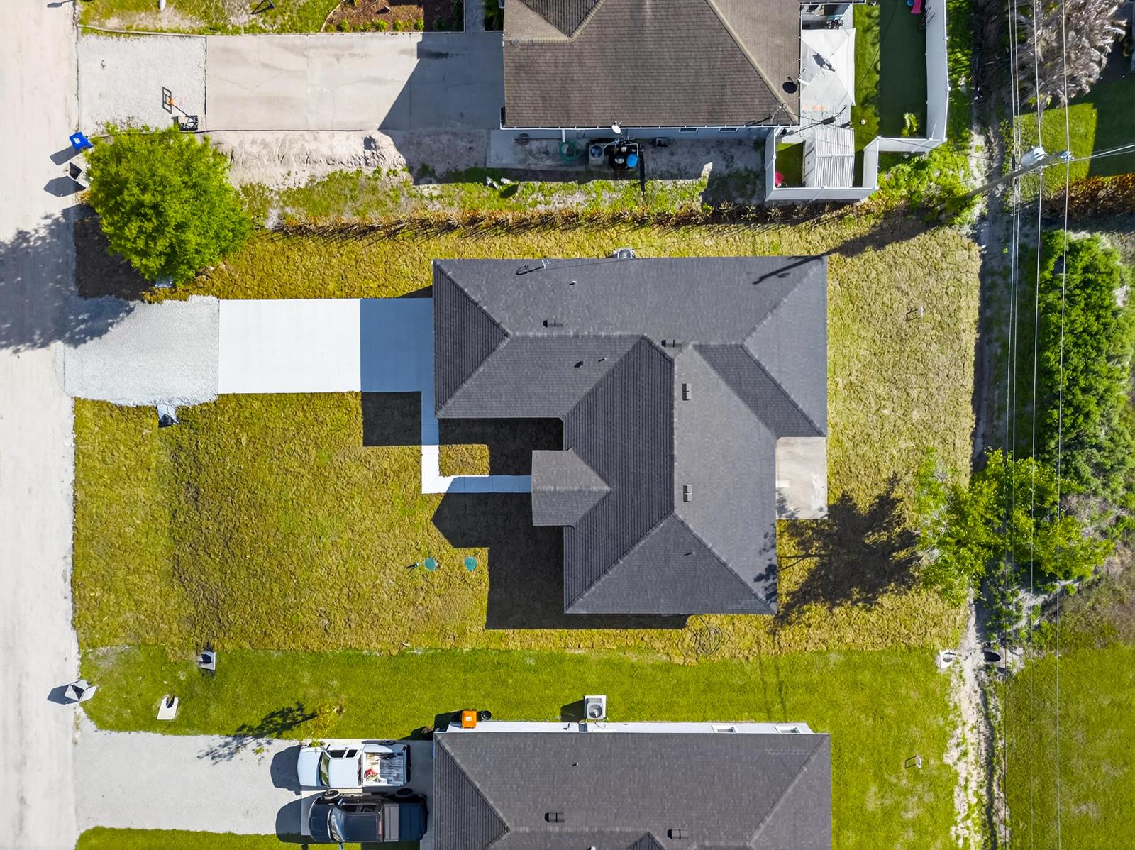An aerial view shows a single-story house with a dark shingled roof and concrete driveway — 7785 105th Avenue, Vero Beach FL 32967, VERO BEACH, FL