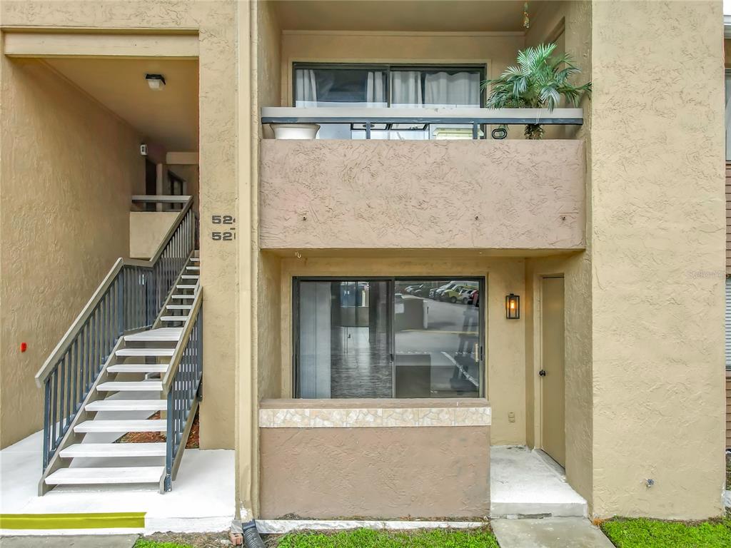 An exterior view of a two-story apartment building with stairs leading to an upper balcony — 5249 VINELAND ROAD, ORLANDO, FL