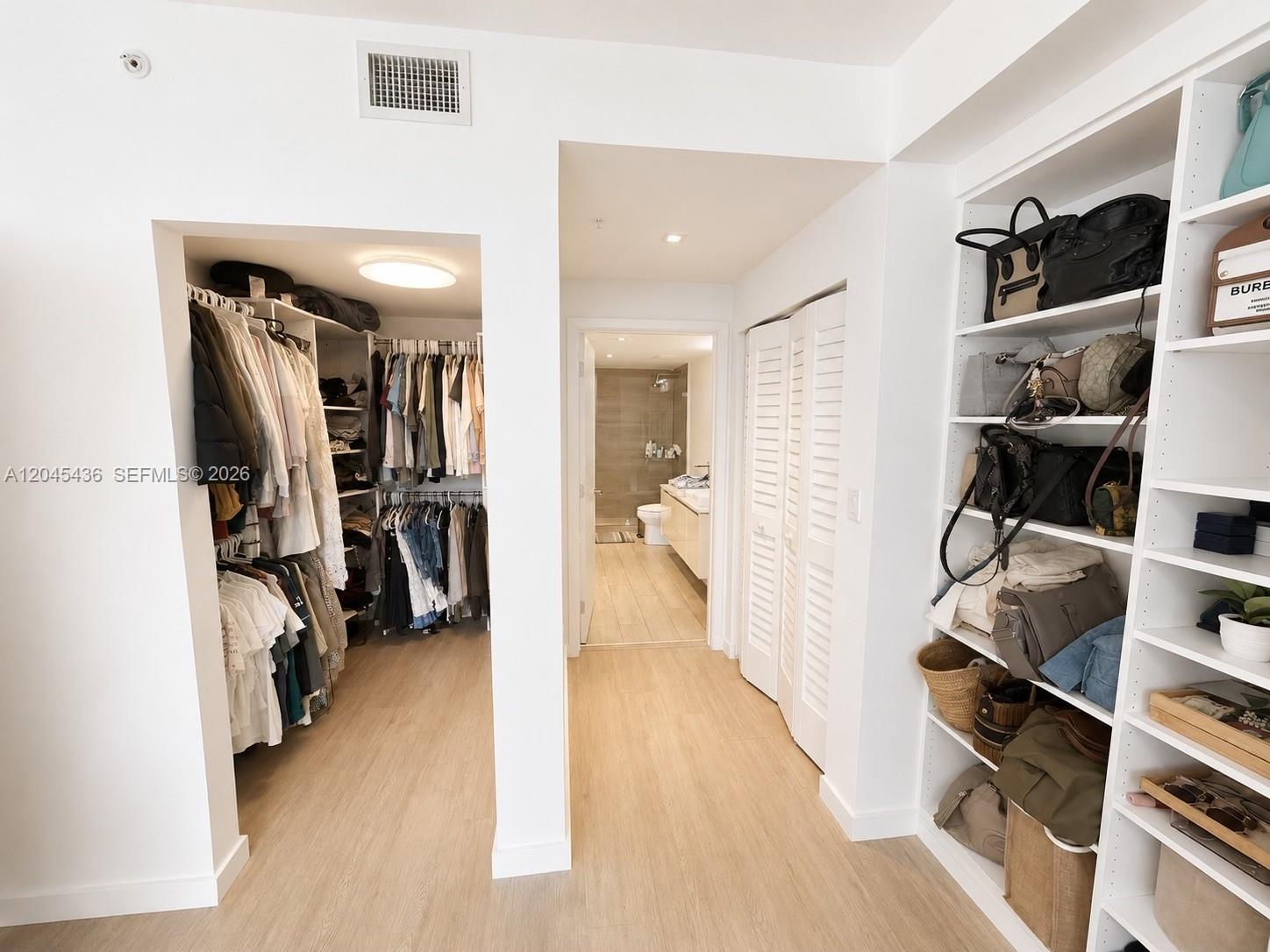 A walk-in closet leads to a bathroom with light wood flooring and white shelving — 1600 SW 1st Ave # 906, Miami FL 33129, MIAMI, FL