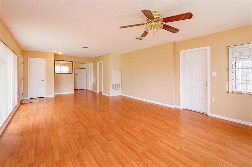 An empty room with light wood-look flooring, beige walls, a ceiling fan, and multiple doors — 1519 CATALPA LANE, ORLANDO, FL
