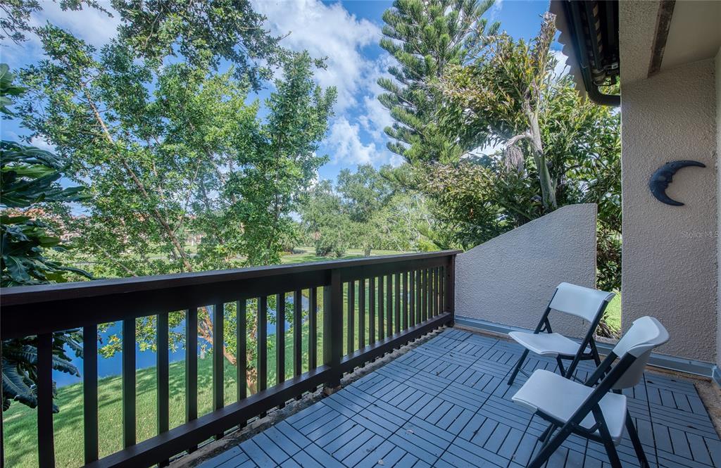 A kitchen with a breakfast bar and a living area featuring a mirrored wall — 1328 PELICAN CREEK CROSSING UNIT D, ST PETERSBURG, FL