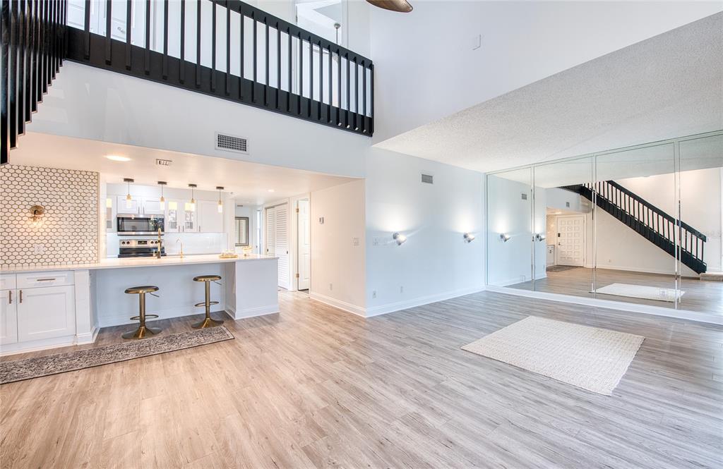 A balcony with dark wooden railings, grey tiled flooring, and two white folding chairs — 1328 PELICAN CREEK CROSSING UNIT D, ST PETERSBURG, FL