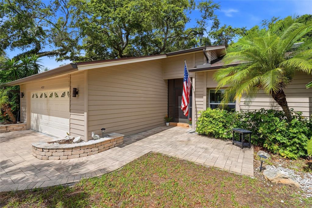 A single-story house with tan horizontal siding, a paved driveway, and a front porch — 4733 LAKE VALENCIA BOULEVARD W, PALM HARBOR, FL