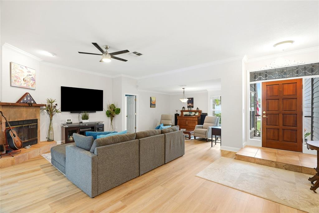 A living room features light wood flooring, a gray sectional sofa, and a stone fireplace — 4733 LAKE VALENCIA BOULEVARD W, PALM HARBOR, FL