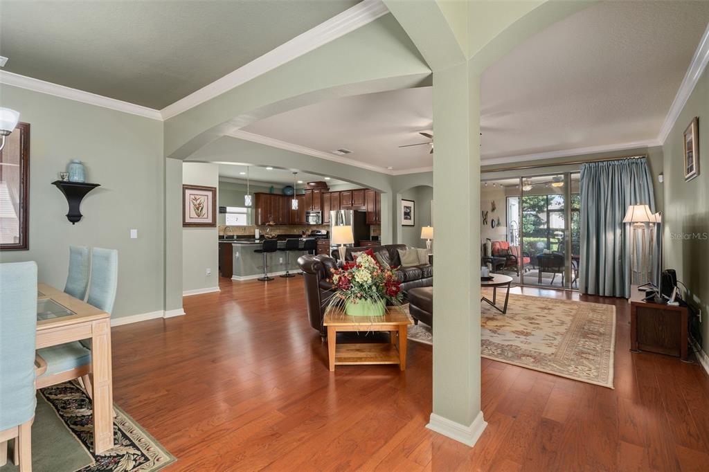 An open-concept living area features hardwood floors, a dining space, and a kitchen with bar seating — 2594 STARGRASS CIRCLE, CLERMONT, FL