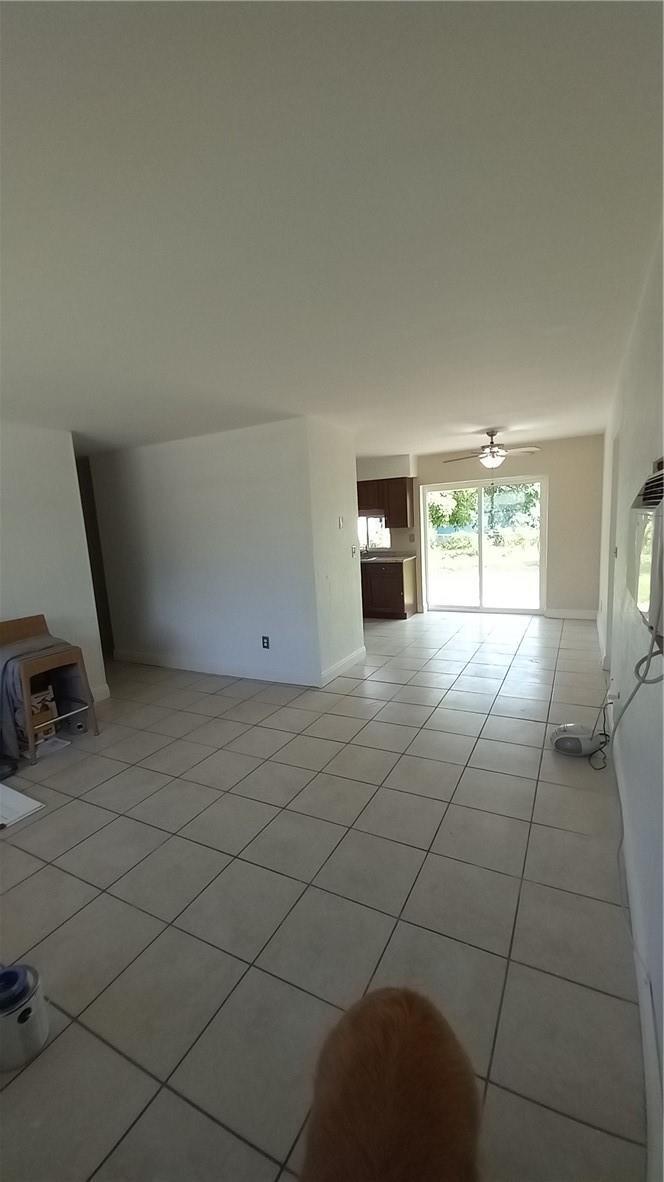 An open-concept living and dining area features light-colored tile flooring and a sliding glass door — 330 NW 38th Street, Deerfield Beach FL 33064, DEERFIELD BEACH, FL