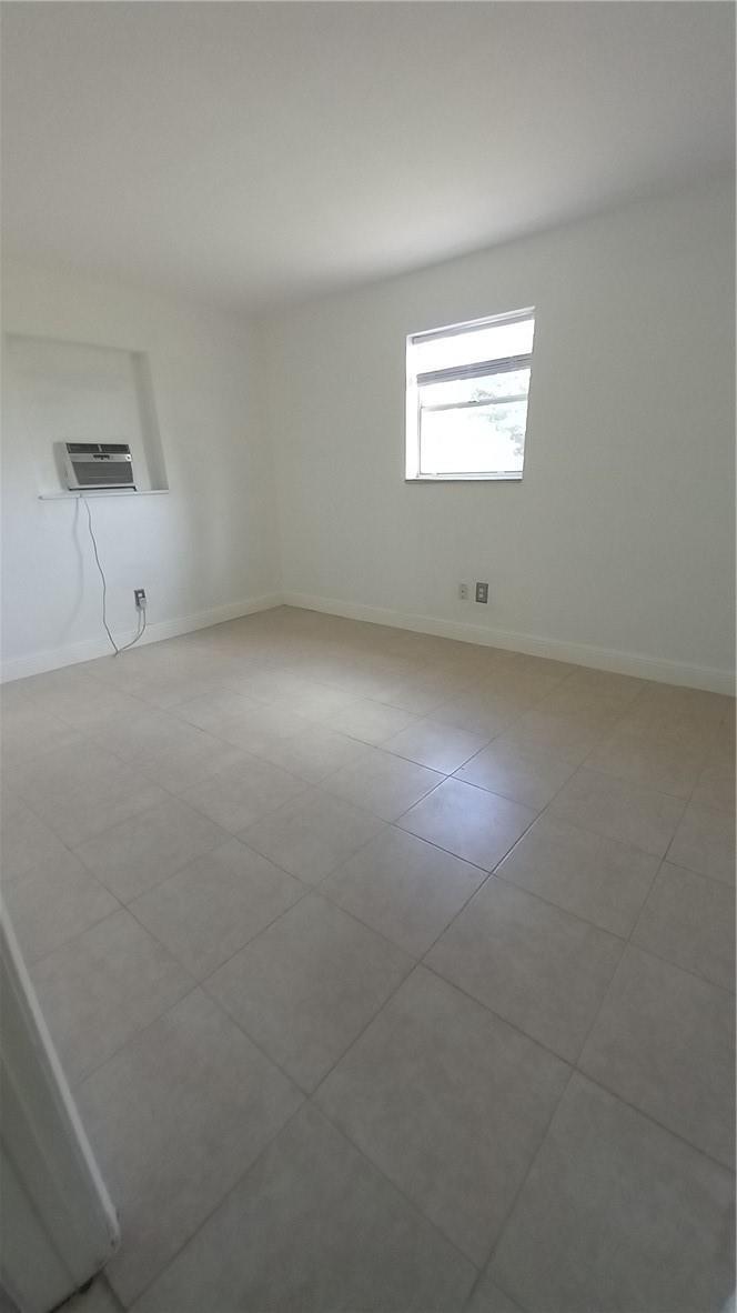 An empty room with white walls, light-colored tile flooring, and a window-mounted air conditioner — 330 NW 38th Street, Deerfield Beach FL 33064, DEERFIELD BEACH, FL