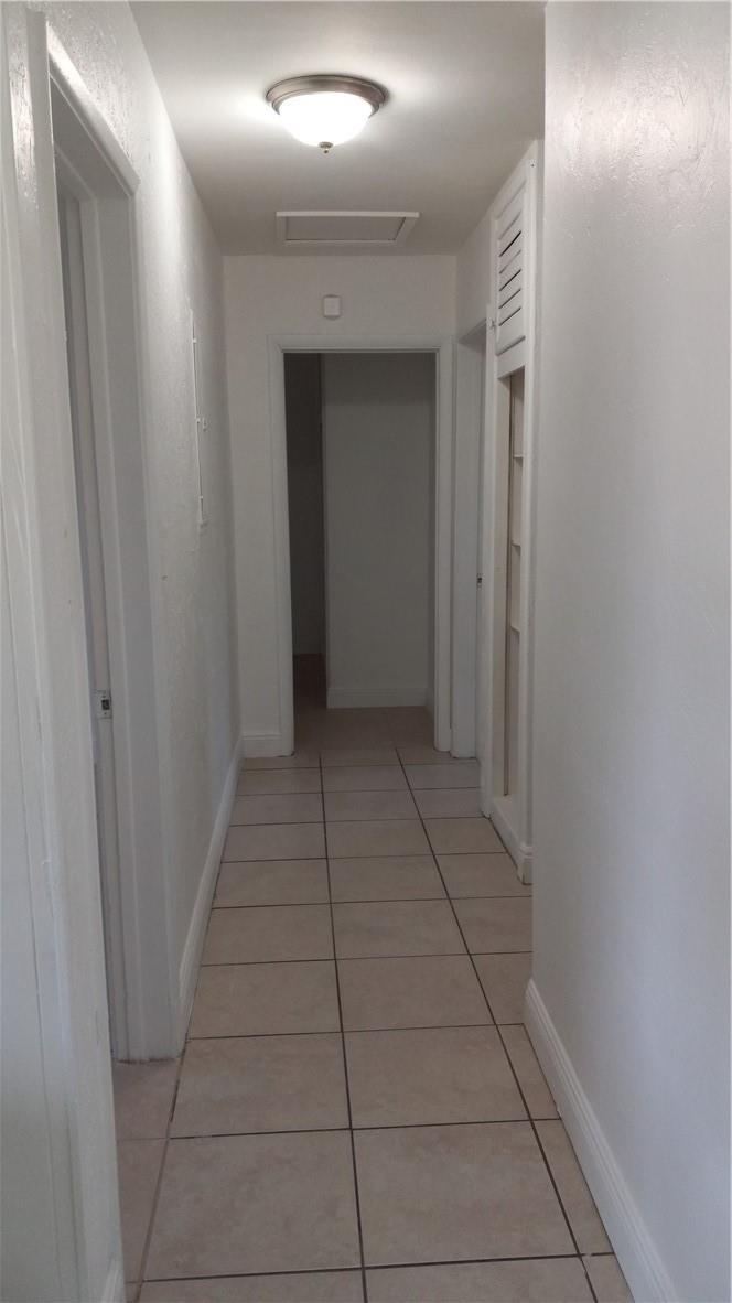 A hallway with light-colored floor tiles, white walls, and a ceiling light fixture — 330 NW 38th Street, Deerfield Beach FL 33064, DEERFIELD BEACH, FL