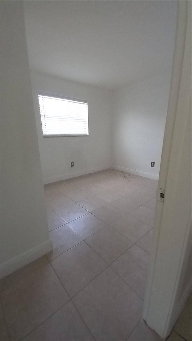 An empty room features white walls, a single window with blinds, and light-colored tile flooring — 330 NW 38th Street, Deerfield Beach FL 33064, DEERFIELD BEACH, FL