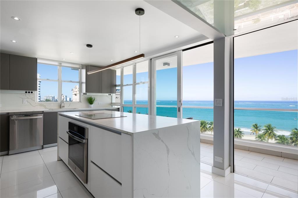 A modern kitchen with a white marble island overlooks the ocean from a balcony — 5575 AVENIDA ISLA VERDE UNIT 903, CAROLINA, PR