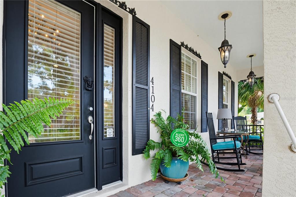 A covered front porch features a black door, rocking chairs, and a potted fern — 4104 SARASOTA AVENUE, SARASOTA, FL