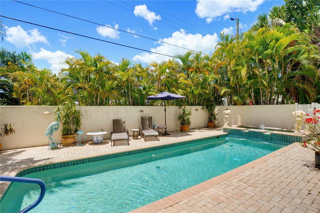 A rectangular swimming pool with a fountain feature sits on a paved patio with palm trees — 4104 SARASOTA AVENUE, SARASOTA, FL
