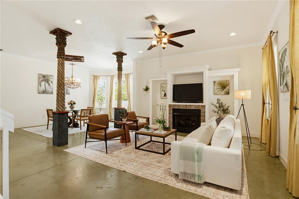 A bright open-concept living and dining area features decorative columns, a fireplace, and concrete floors — 4104 SARASOTA AVENUE, SARASOTA, FL