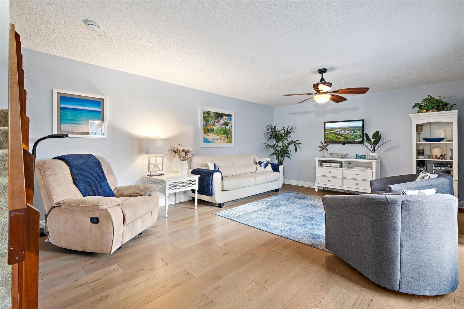 A living room features light blue walls, wood flooring, a beige sofa, and two armchairs — 3840 SE Jefferson Street, Stuart FL 34997, STUART, FL