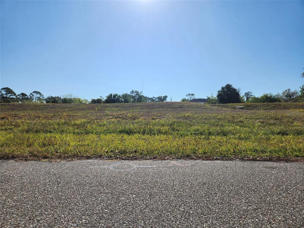 A view from the street looking up at a vacant, grassy residential lot — 155 JADE STREET, ROTONDA WEST, FL