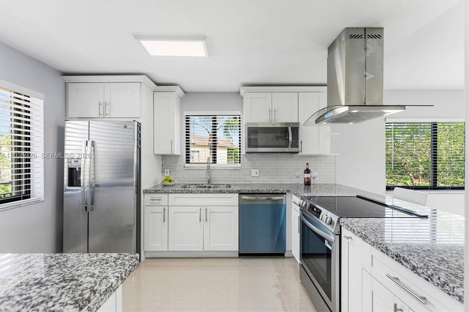A kitchen features white cabinets, granite countertops, stainless steel appliances, and a tile backsplash — 16451 Blatt Blvd # 201, Weston FL 33326, WESTON, FL