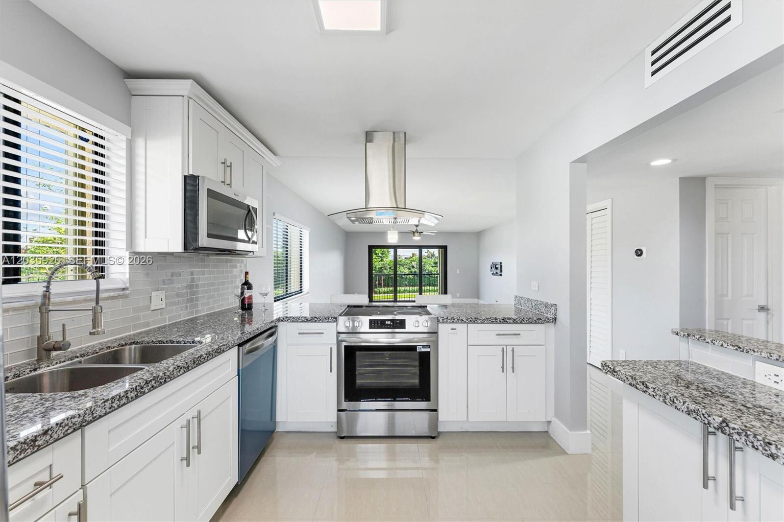 A modern kitchen features white cabinets, granite countertops, stainless steel appliances, and a range hood — 16451 Blatt Blvd # 201, Weston FL 33326, WESTON, FL