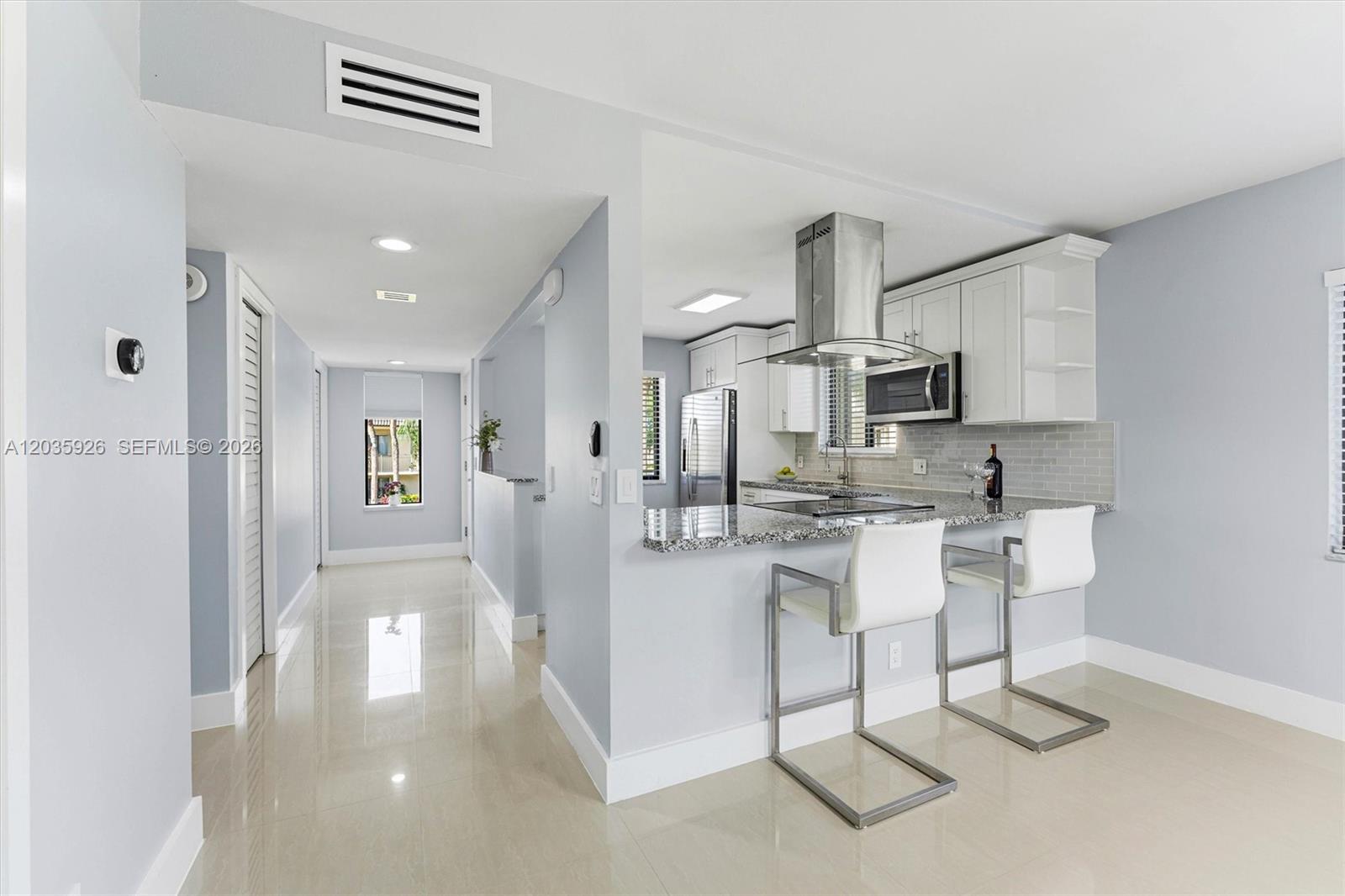 A kitchen with a granite breakfast bar, white cabinets, and stainless steel appliances — 16451 Blatt Blvd # 201, Weston FL 33326, WESTON, FL