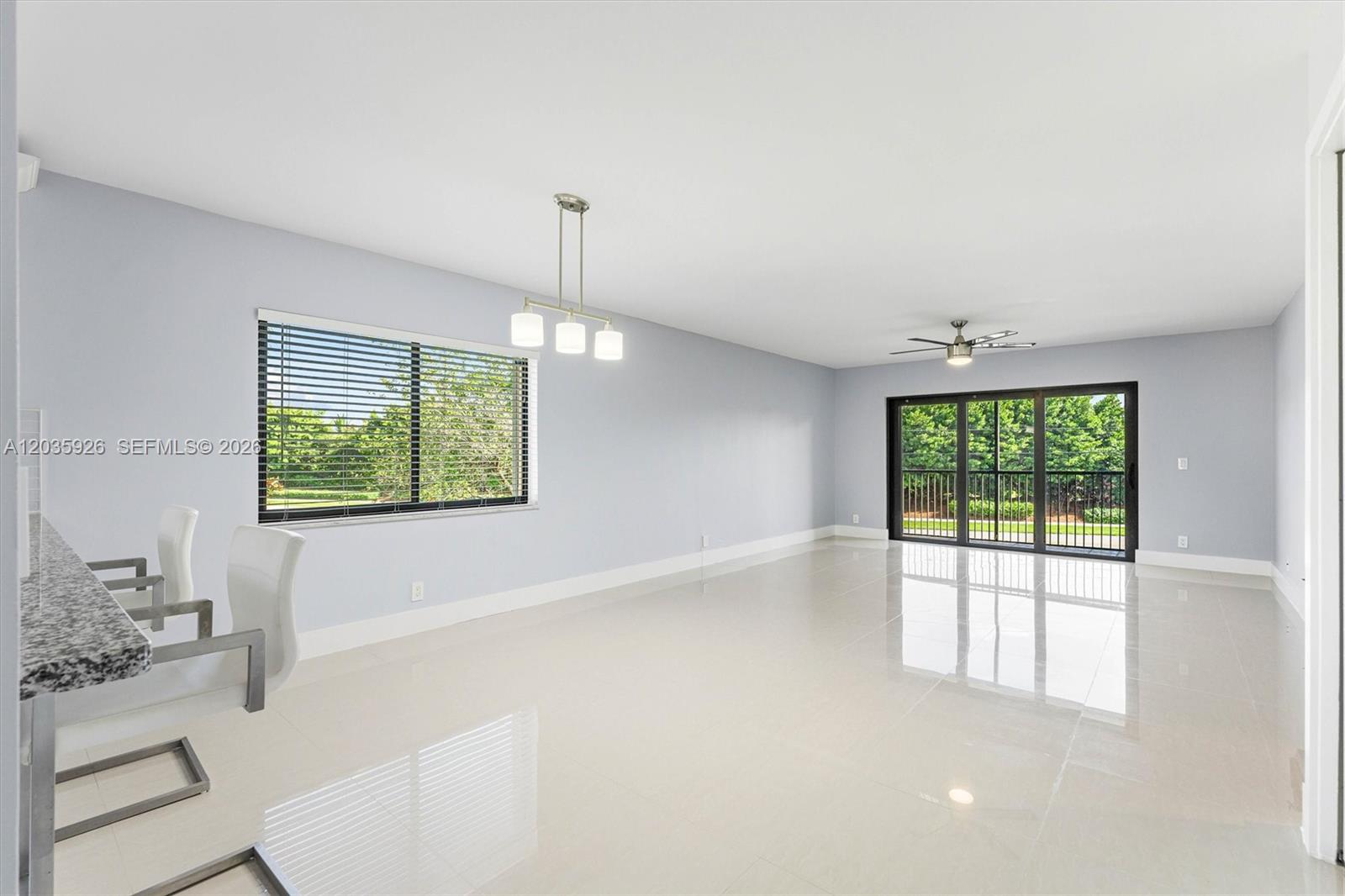 An open-concept dining area features light gray walls, white tile flooring, and a sliding glass door — 16451 Blatt Blvd # 201, Weston FL 33326, WESTON, FL