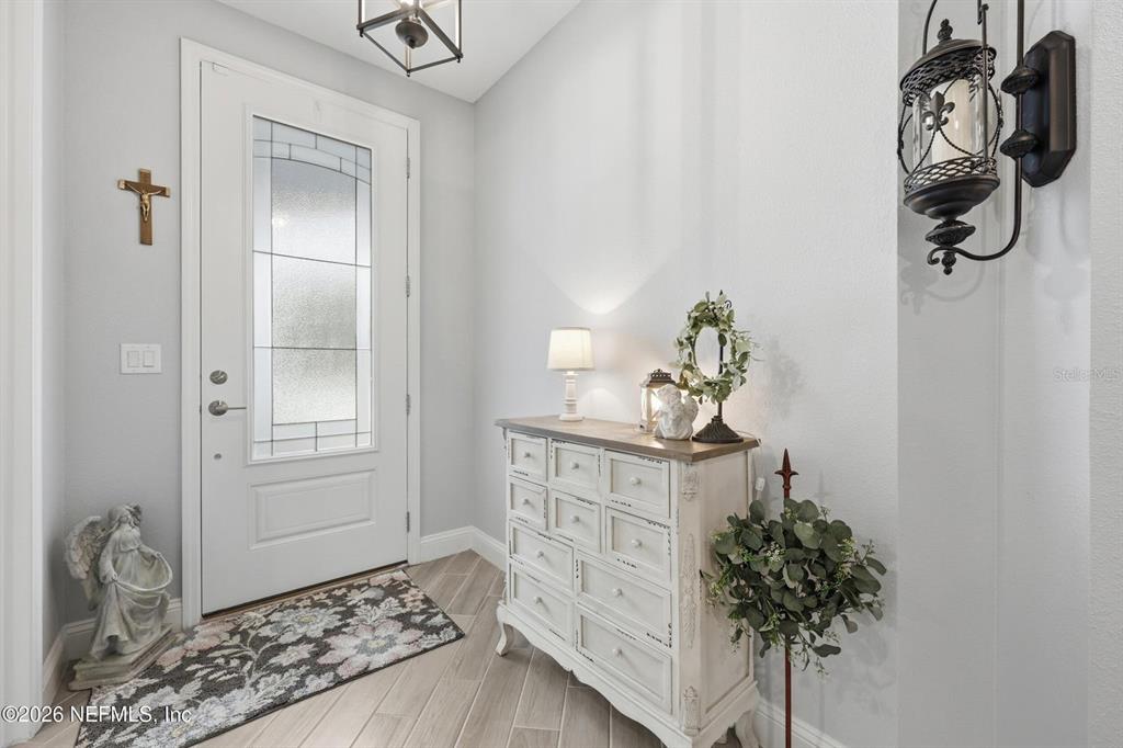 This entryway features a white front door, a wooden chest, and decorative wall sconces — 312 STILLWATER BOULEVARD, ST JOHNS, FL