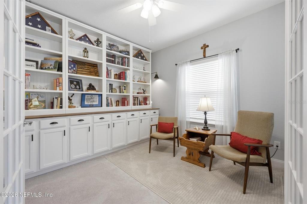 A home office features built-in white shelving, two armchairs, and a window with curtains — 312 STILLWATER BOULEVARD, ST JOHNS, FL
