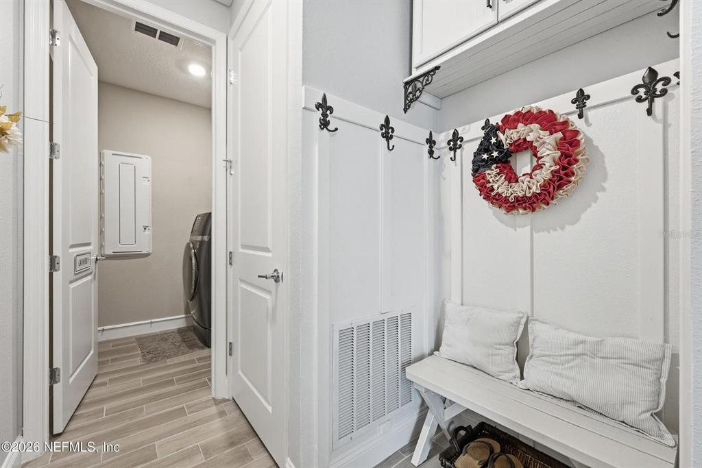 A mudroom area features a white bench, wall hooks, and a doorway to a laundry room — 312 STILLWATER BOULEVARD, ST JOHNS, FL