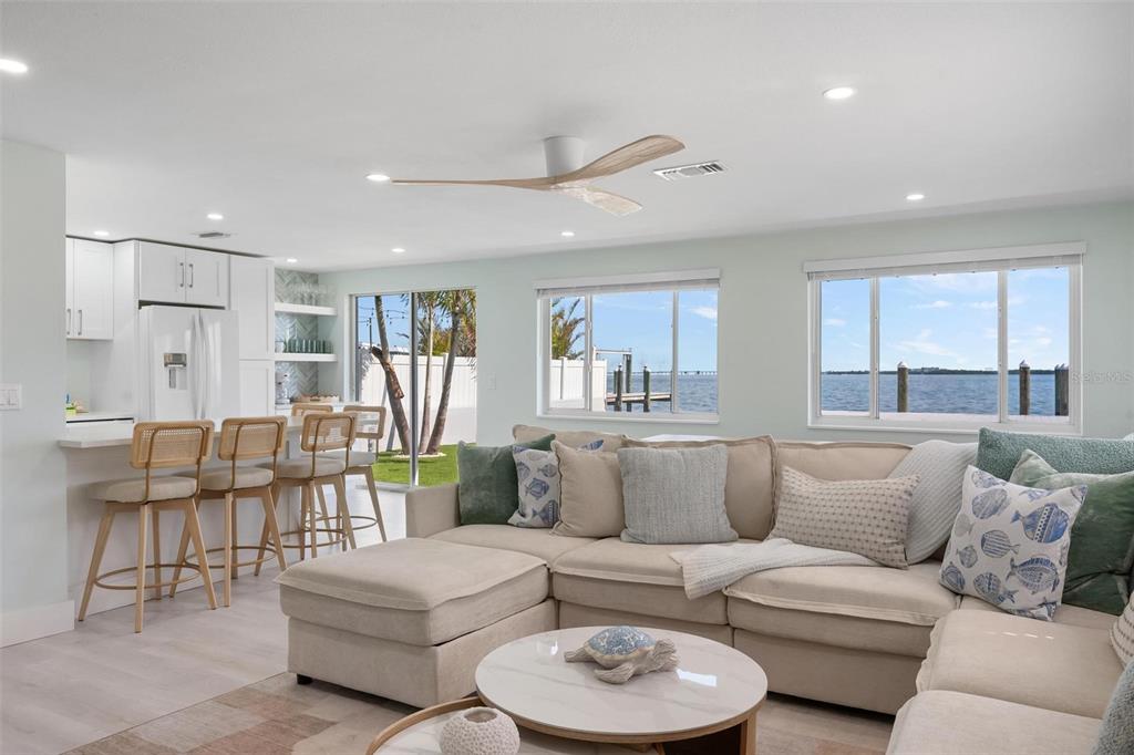 A living room with a sectional sofa and kitchen bar overlooks a waterfront view — 118 9TH STREET N, BRADENTON BEACH, FL