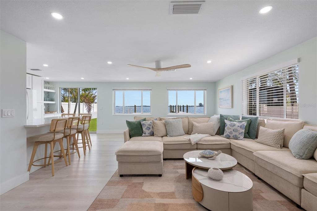 A living room with a sectional sofa, kitchen island, and water views through large windows — 118 9TH STREET N, BRADENTON BEACH, FL