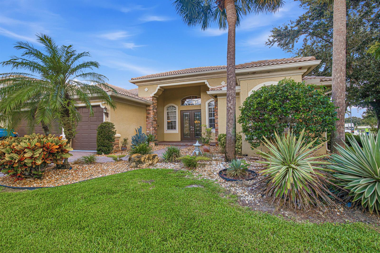 A single-story stucco house with a tile roof, double front doors, and landscaped front yard — LAKE WORTH, FL