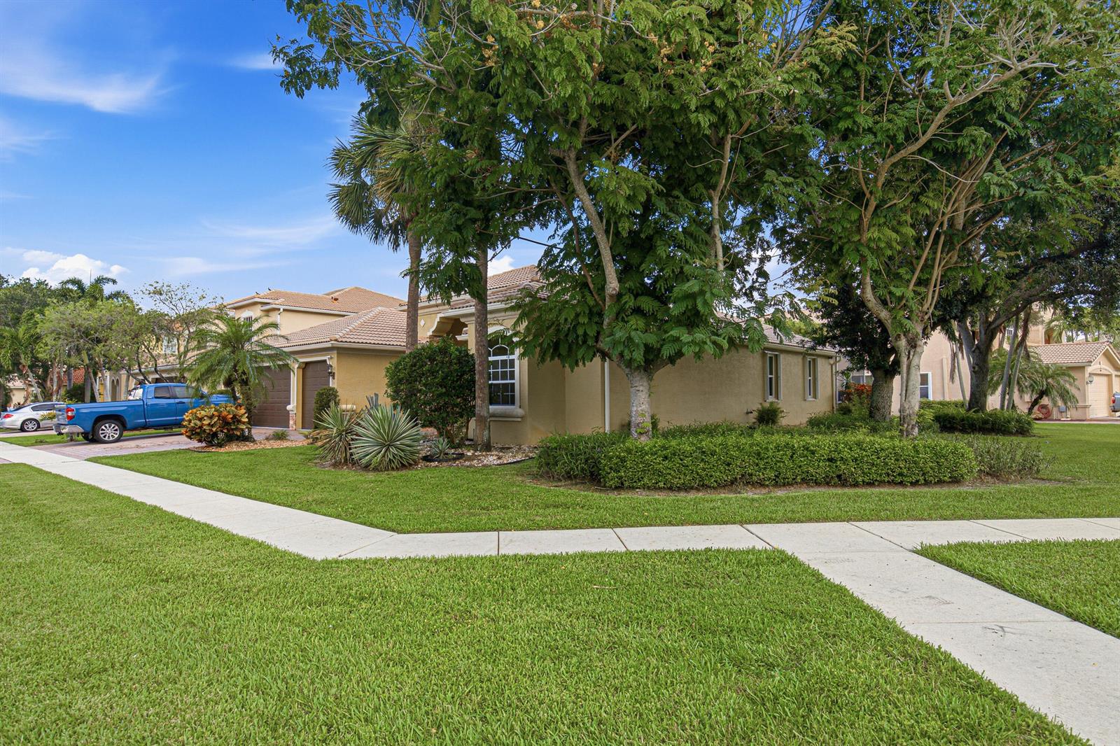 A tan single-story house with a blue pickup truck parked in the driveway — LAKE WORTH, FL