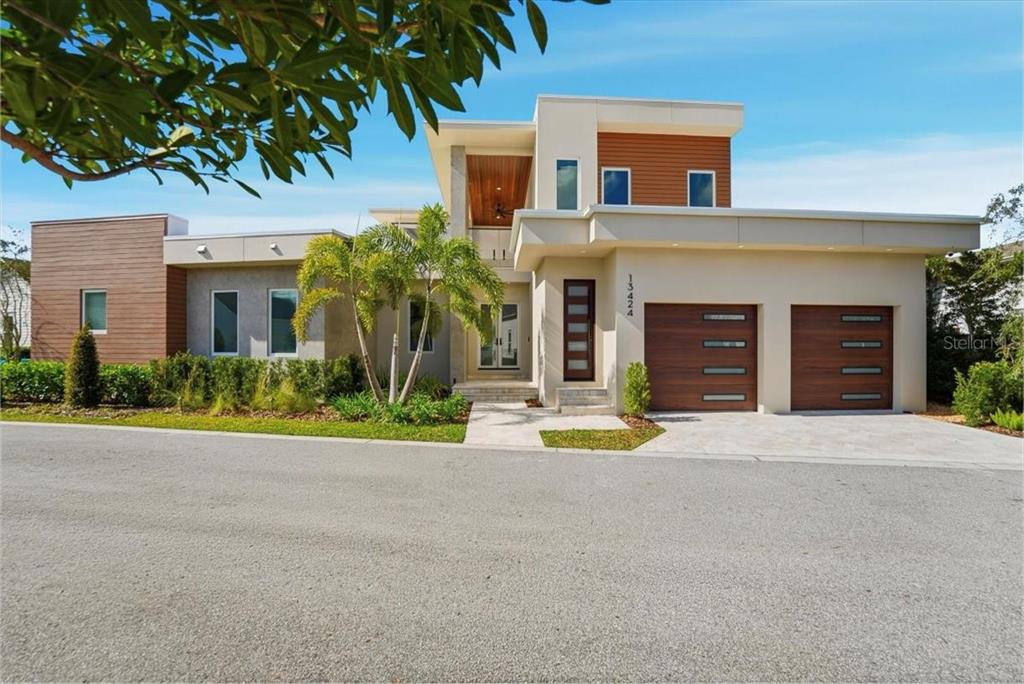 A modern two-story house features a flat roof, wood-paneled accents, and a two-car garage — 13424 BEEBE ALLEY, ORLANDO, FL