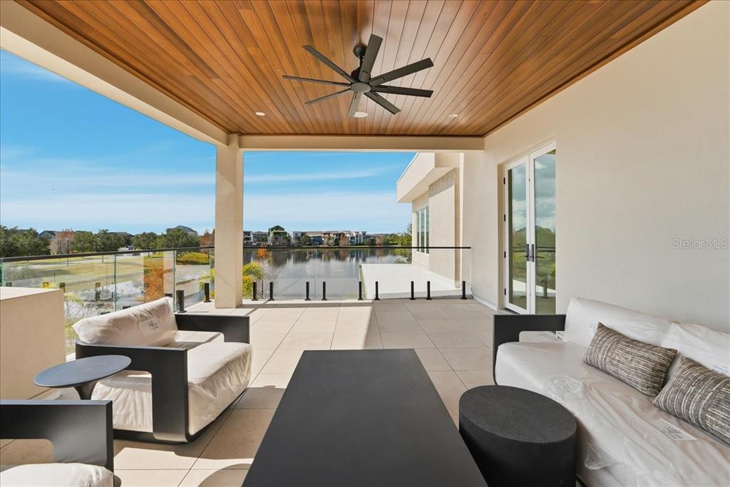 A covered outdoor patio features a wood-paneled ceiling, a ceiling fan, and glass railings — 13424 BEEBE ALLEY, ORLANDO, FL
