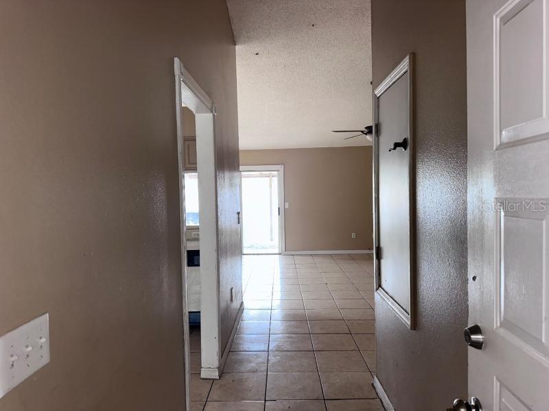 A view from an entryway looking into a tiled living area with a sliding glass door — 1451 MOHRLAKE DRIVE, BRANDON, FL