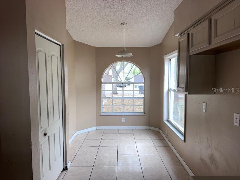 A kitchen dining nook with tile floors, a large arched window, and a pendant light — 1451 MOHRLAKE DRIVE, BRANDON, FL