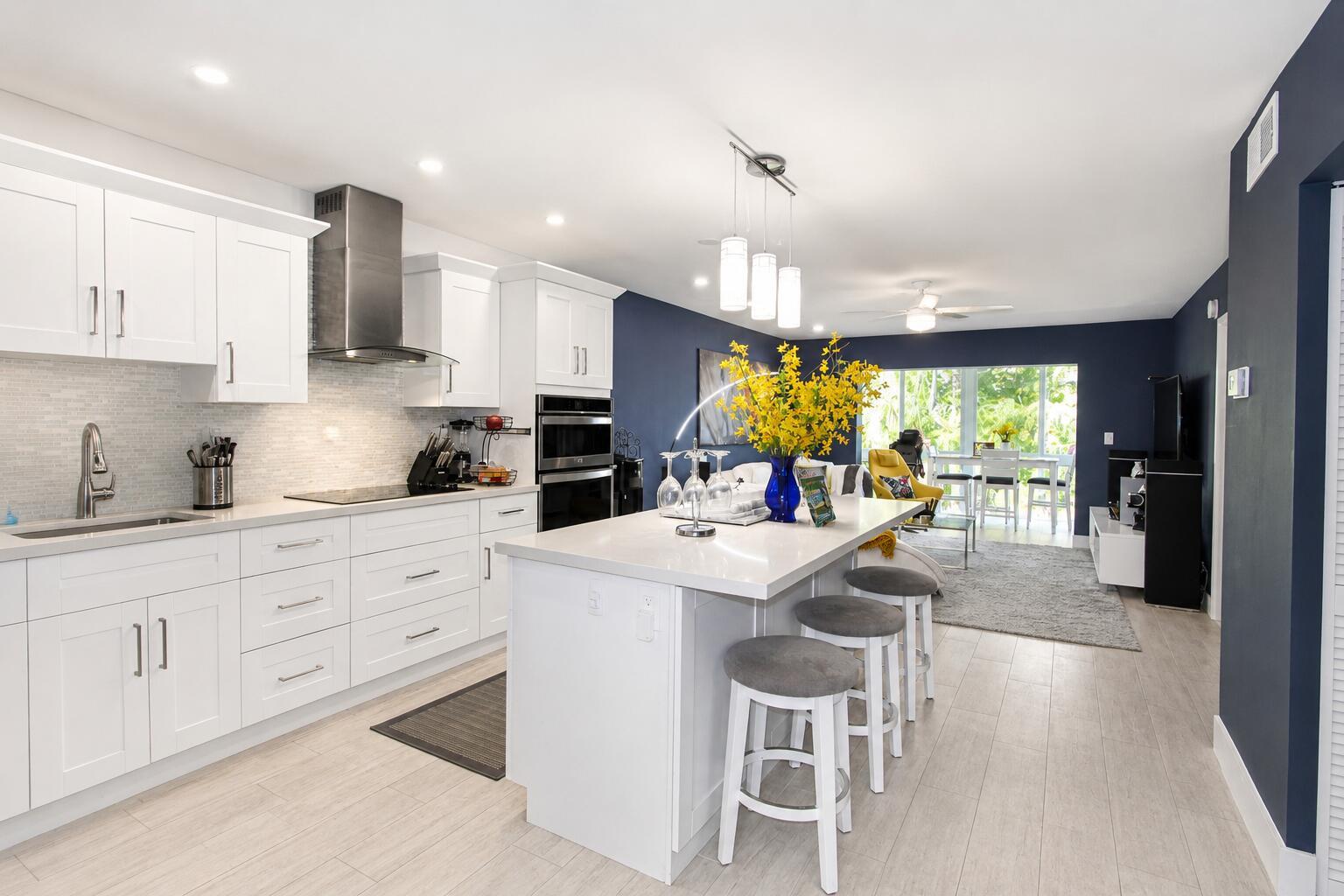 A modern kitchen with white cabinets, a central island, and navy blue accent walls — 7787 Golf Cir Drive # 301, Margate FL 33063, MARGATE, FL