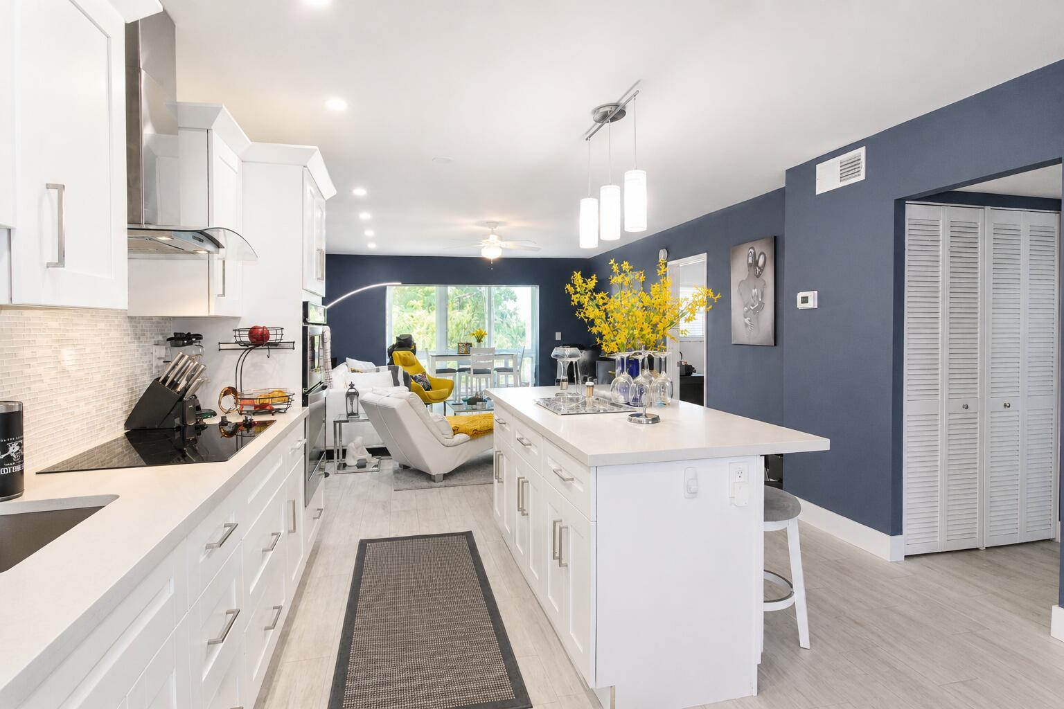 A modern kitchen with white cabinets, a central island, and dark blue accent walls — 7787 Golf Cir Drive # 301, Margate FL 33063, MARGATE, FL
