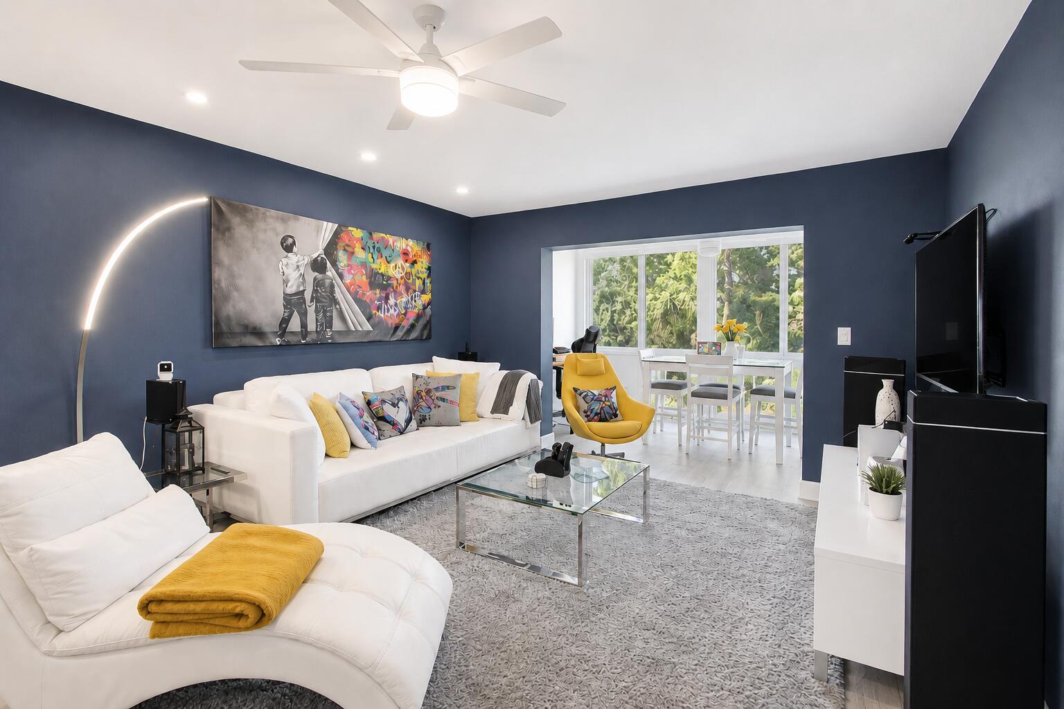 A living room features dark blue walls, a white sofa, a yellow chair, and artwork — 7787 Golf Cir Drive # 301, Margate FL 33063, MARGATE, FL