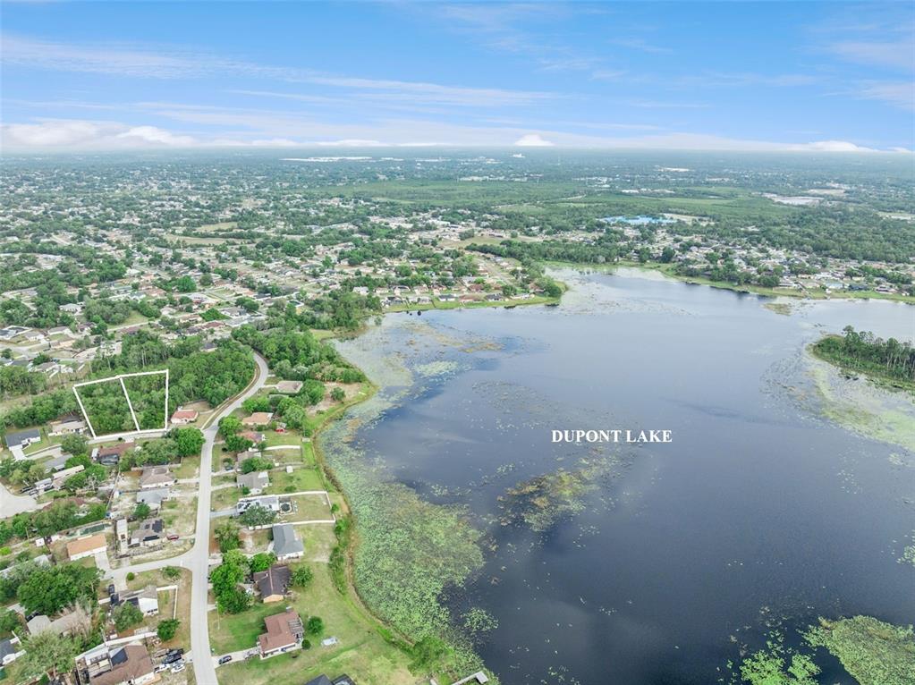 An aerial view shows a vacant lot outlined in white next to Dupont Lake — 1680  & 1672 GREGORY DRIVE, DELTONA, FL